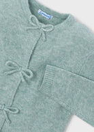 Green cardigan with bow details on a white background