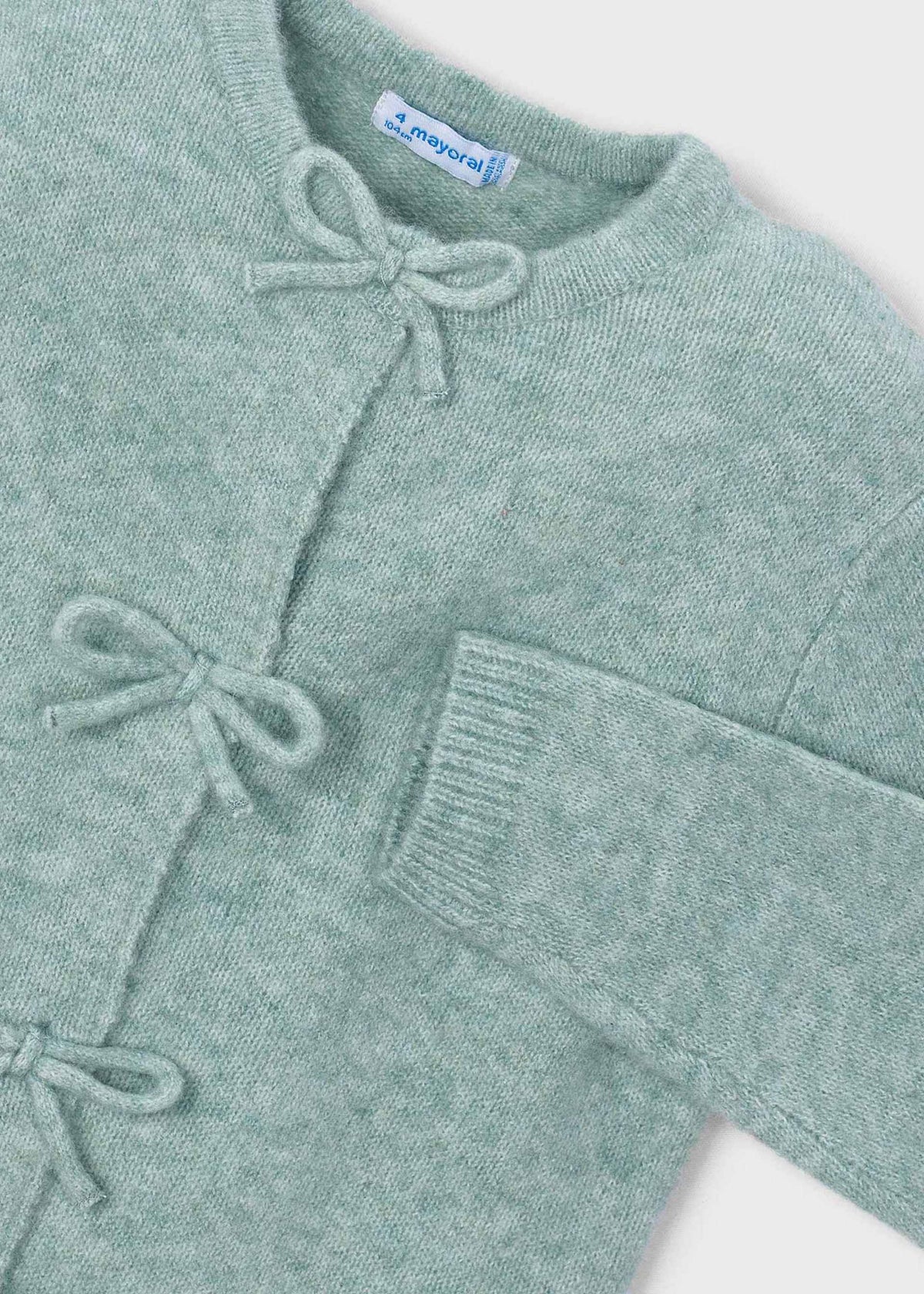 Green cardigan with bow details on a white background