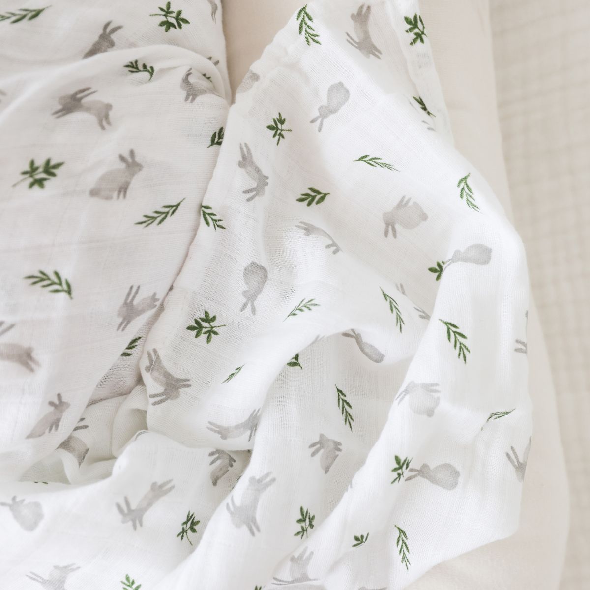 White fabric with gray rabbit and green leaf pattern on a beige background