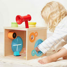 Child playing with a wooden toy box with colorful components