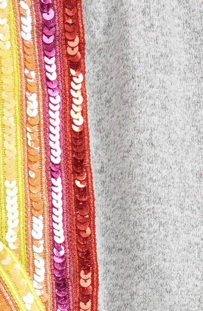 Close-up of colorful sequin trim on a gray fabric background