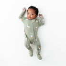 Baby wearing a green onesie with animal patterns on a white background
