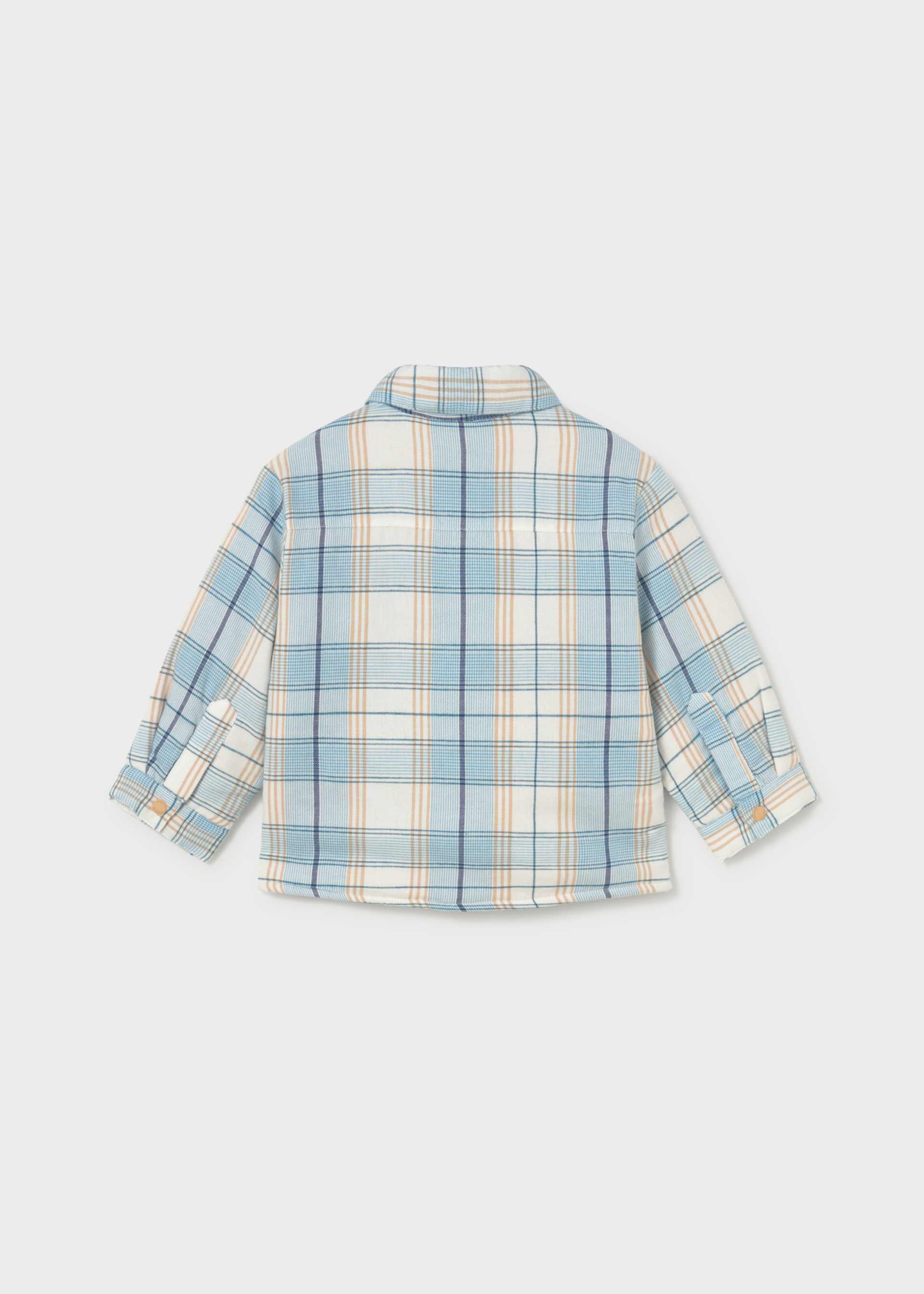 A children's long-sleeve plaid shirt shown from the back, featuring a light blue, cream, and white checkered pattern with thin orange stripes, photographed on a light gray background.