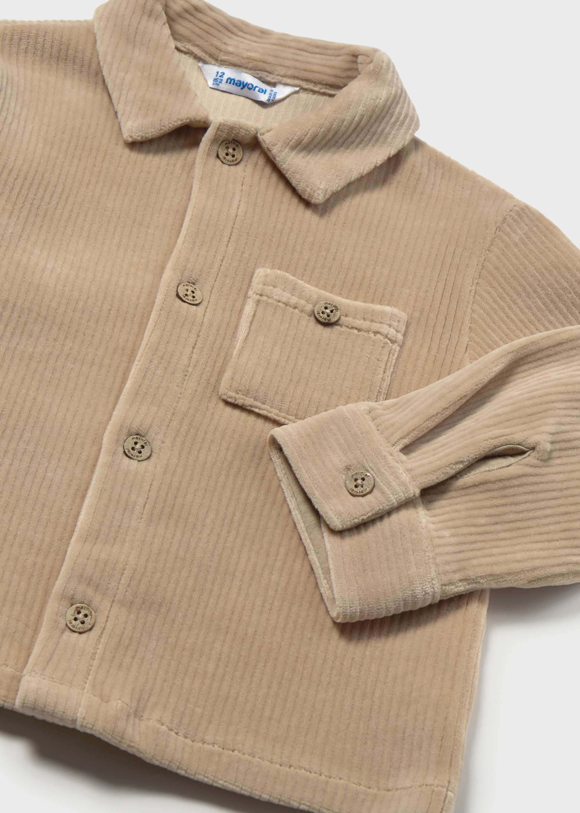 A close-up of a beige corduroy button-up shirt jacket with a collar, chest pocket, and buttoned cuffs, laid flat on a light background.
