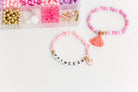 Princess Party DIY Bracelet Kit featuring an open compartment storage box filled with colorful beads, alphabet letter beads, and charms next to two completed beaded bracelets, including one with a tassel charm and one spelling "PRINCESS".