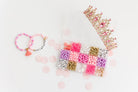 Princess Party DIY Bracelet Kit featuring an open compartment storage box filled with colorful beads, alphabet letter beads, and charms, accompanied by two completed beaded bracelets (one with a tassel) and a decorative gold tiara crown on a light background.