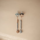 Two baby pacifiers with beaded chains on a beige background