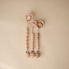 Pink baby teething ring with beads on a beige background