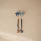 Two baby pacifiers with beaded chains on a beige background