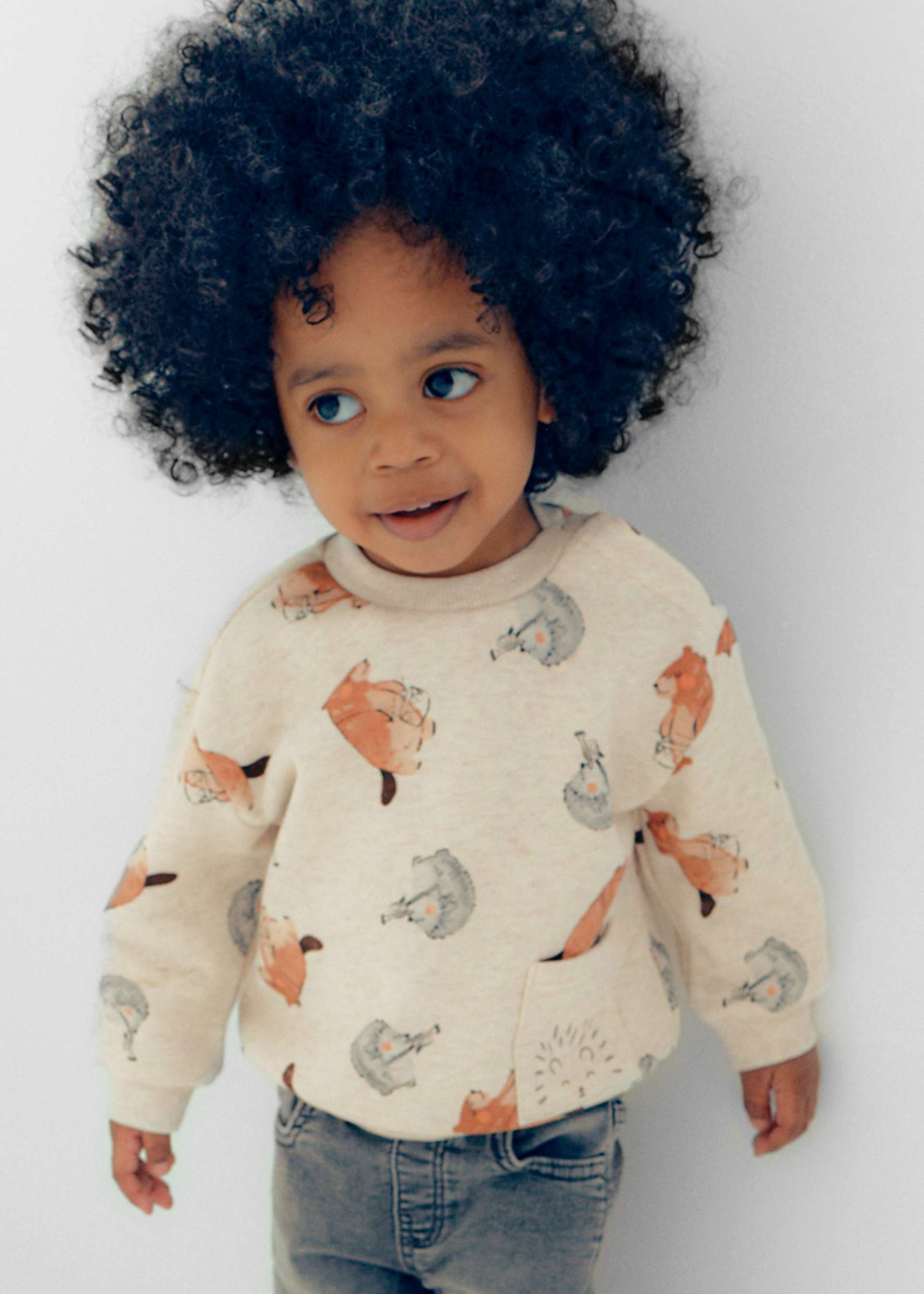 Child wearing a sweater with fox pattern on a plain background