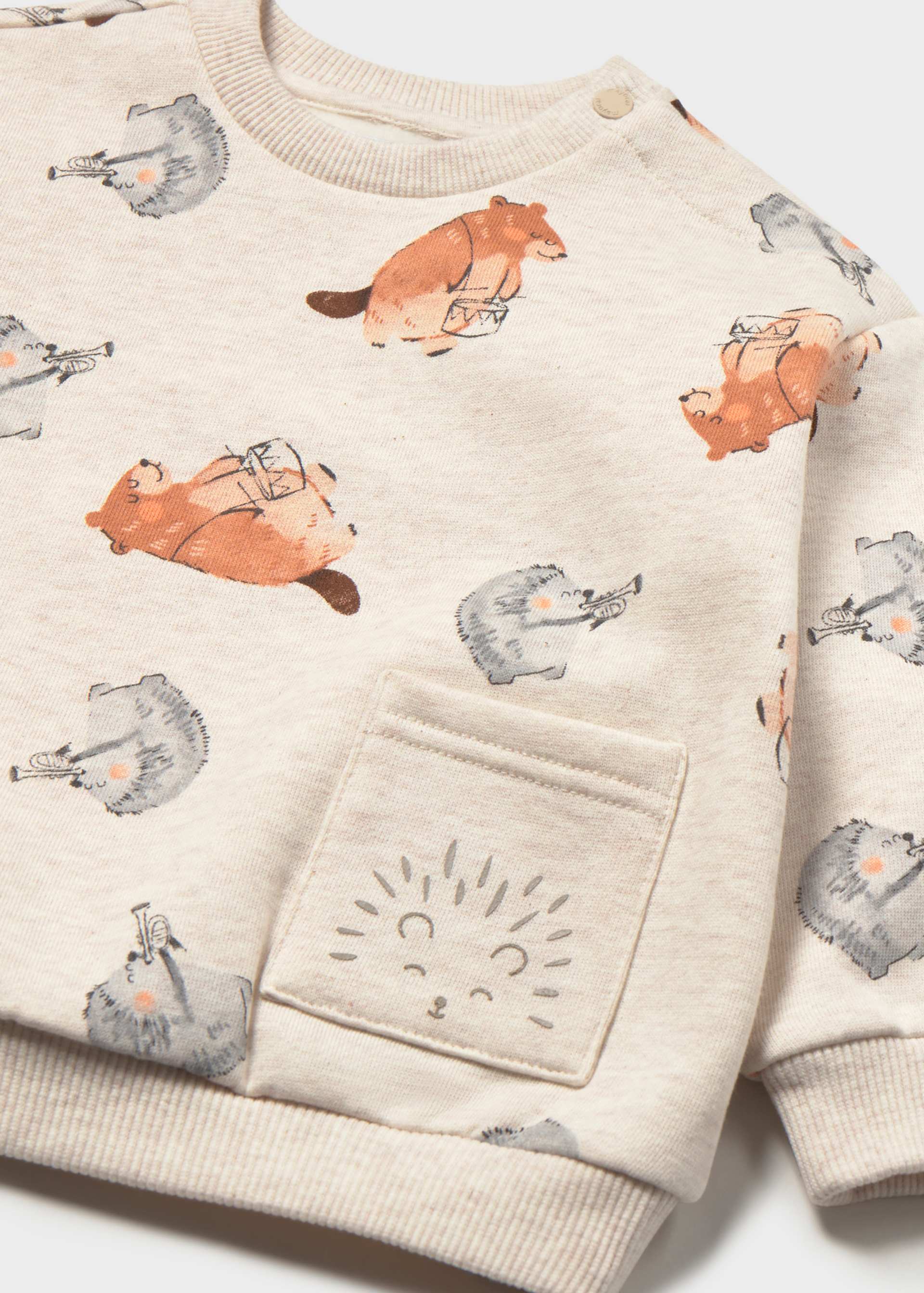 A close-up of a children's cream sweatshirt featuring an all-over print of orange hedgehogs and gray rabbits, with a front pocket decorated with a stitched hedgehog face.