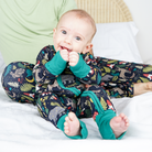 Baby wearing a forest-themed onesie on a white blanket