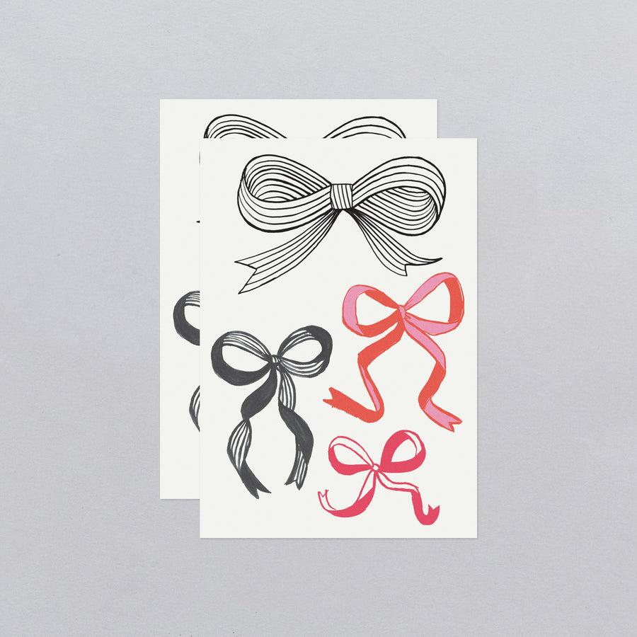 Two sheets of paper with black and red bow designs on a gray background