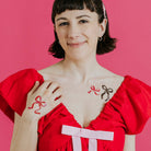 Woman wearing a red dress with bow designs on a pink background