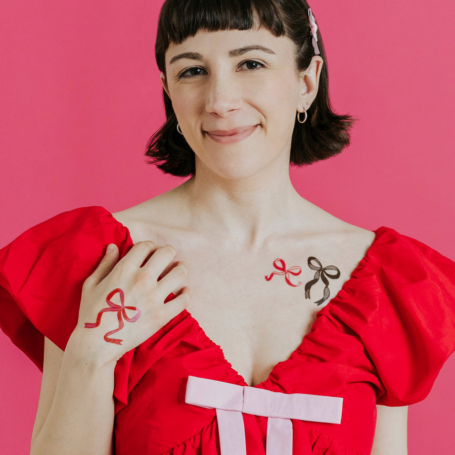 Woman wearing a red dress with bow designs on a pink background