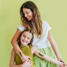 Woman and young girl with green designs on their arms against a light green background