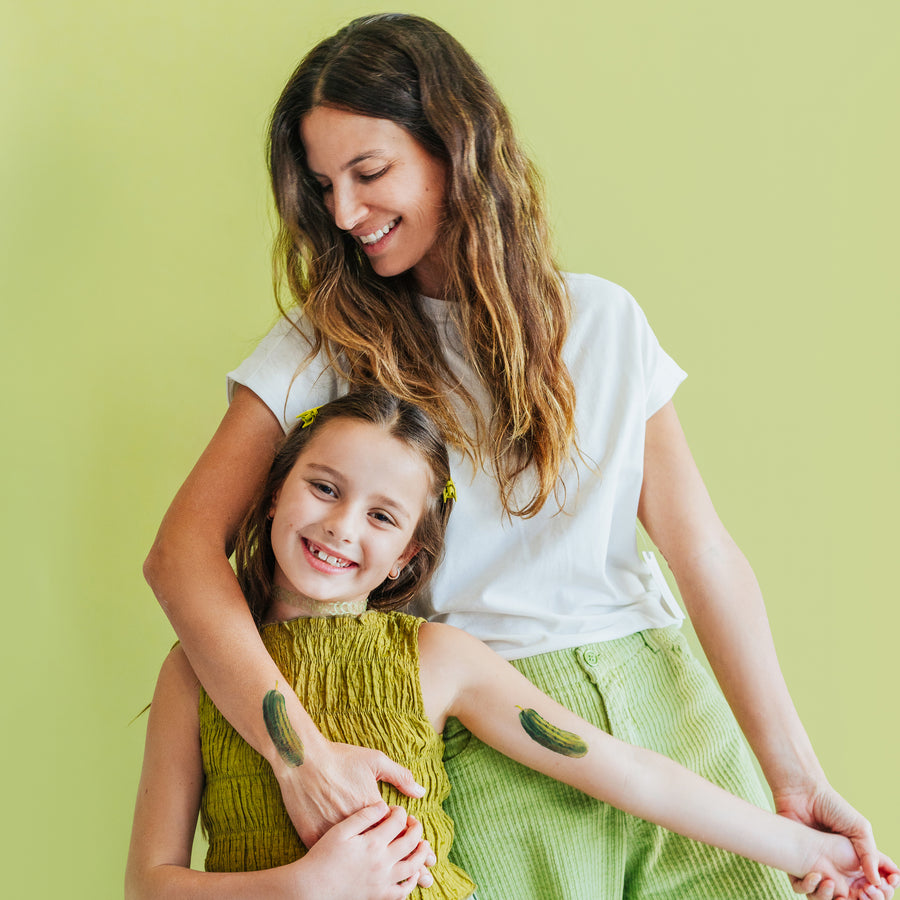 Woman and young girl with green designs on their arms against a light green background