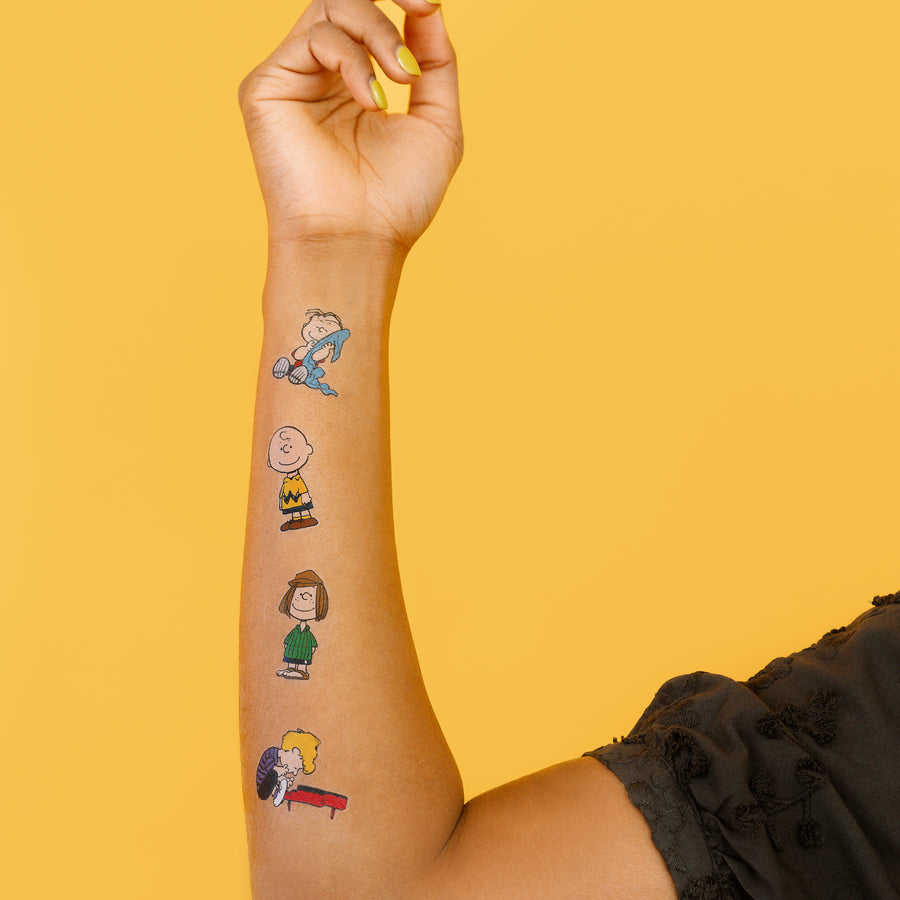 Hand with temporary tattoos of cartoon characters on a yellow background