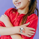 Child wearing a Snoopy temporary tattoo on a purple background