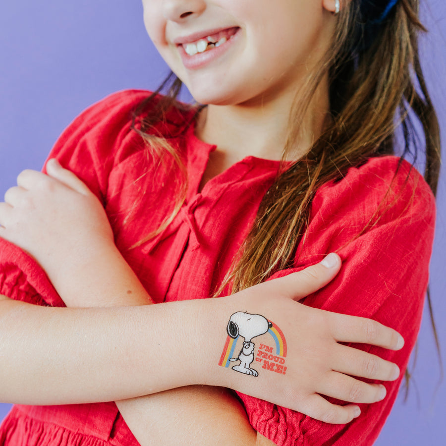 Child wearing a Snoopy temporary tattoo on a purple background