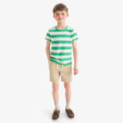Child wearing a green and white striped shirt with beige shorts on a white background