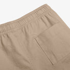 Close-up of beige shorts with a pocket on a light gray background