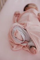 Newborn baby wrapped in a pink blanket on a soft surface