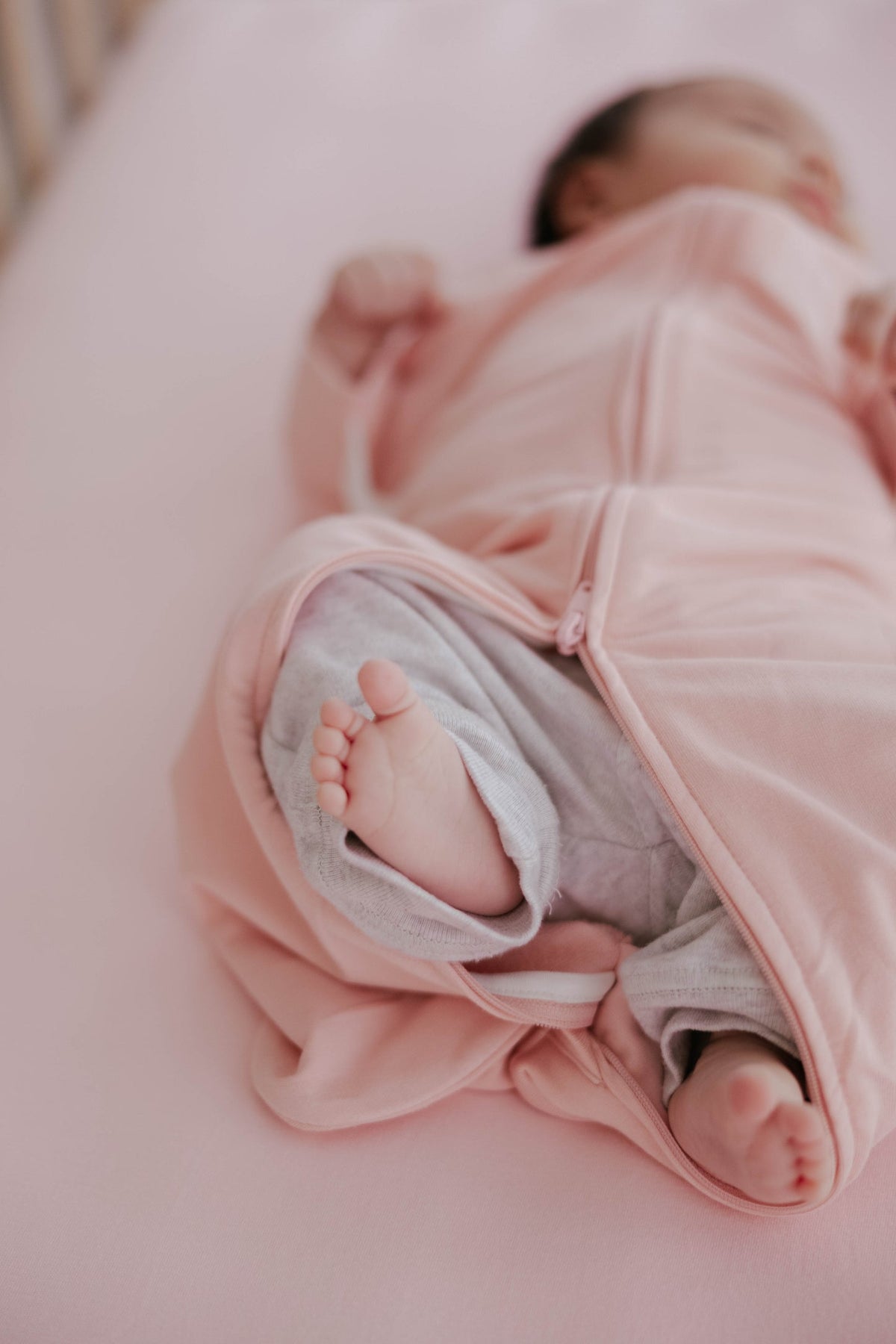 Newborn baby wrapped in a pink blanket on a soft surface