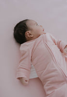 Baby wrapped in a pink blanket lying on a light pink surface