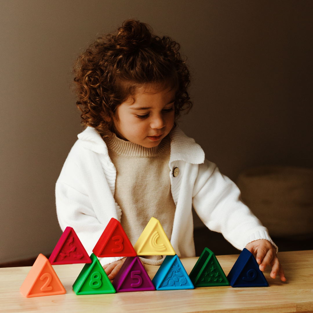 Child playing with colorful triangular blocks on a wooden table