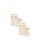 Pair of cream knitted baby booties on a white background