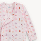 A long-sleeve baby wrap jacket in light pink, featuring an all-over playful print of teddy bears, elephants, and baby booties in pink, purple, and brown. The brand 'EazyFriendly' is visible on the inner neck label.