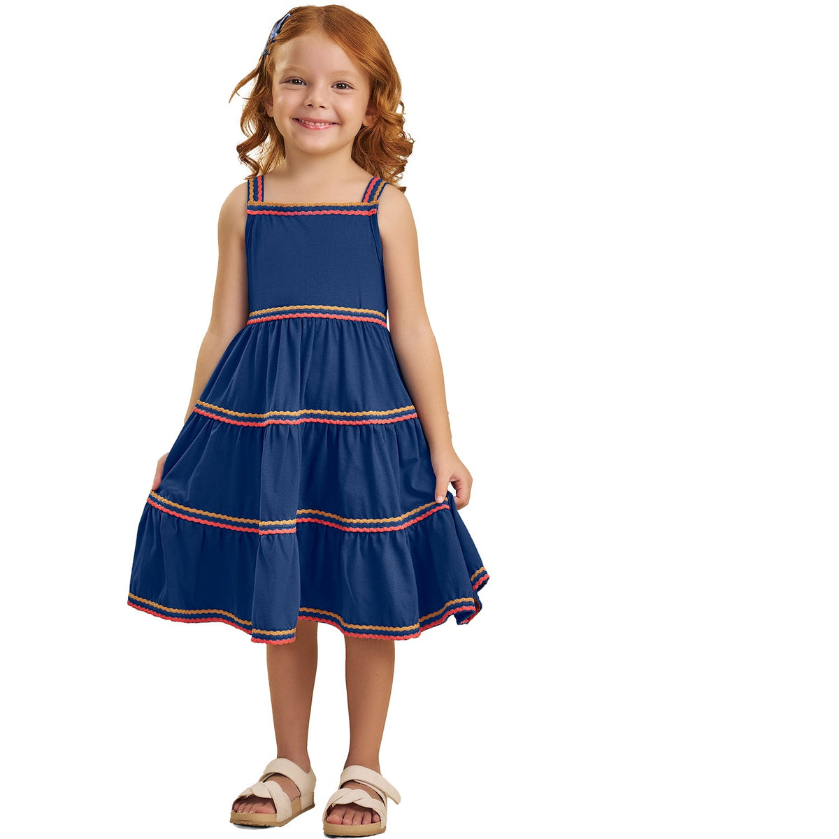 Young girl wearing a blue dress with red and gold trim on a white background