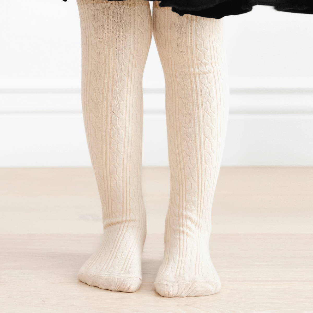 White tights worn by a person on a neutral background
