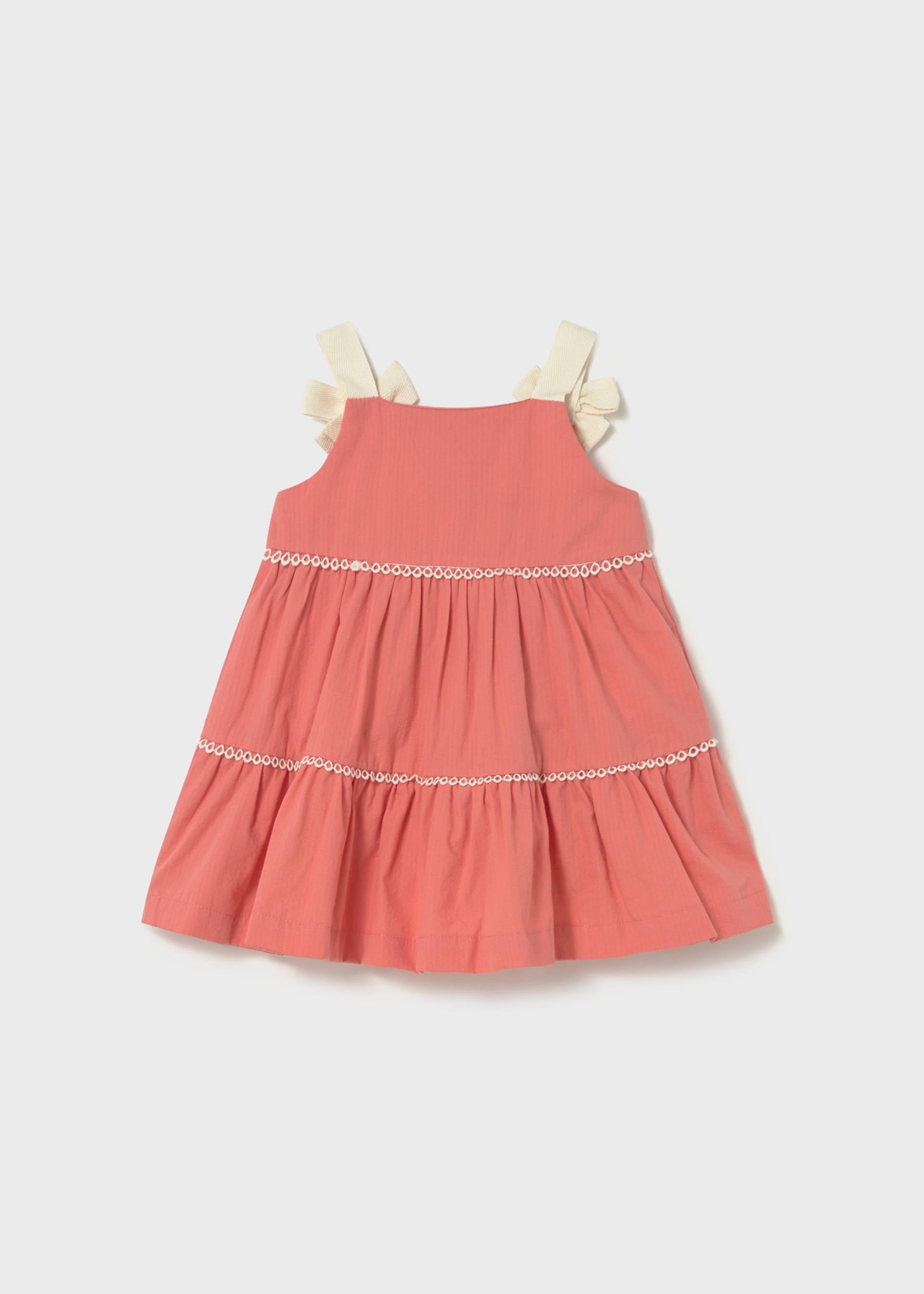 Coral dress with white trim on a light gray background