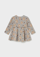 A toddler's long-sleeve peplum dress in heather gray fabric, featuring an all-over print of teddy bears and small hearts in beige and brown, shown against a light gray background.