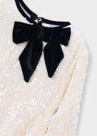 Black velvet bow on a white sequin background