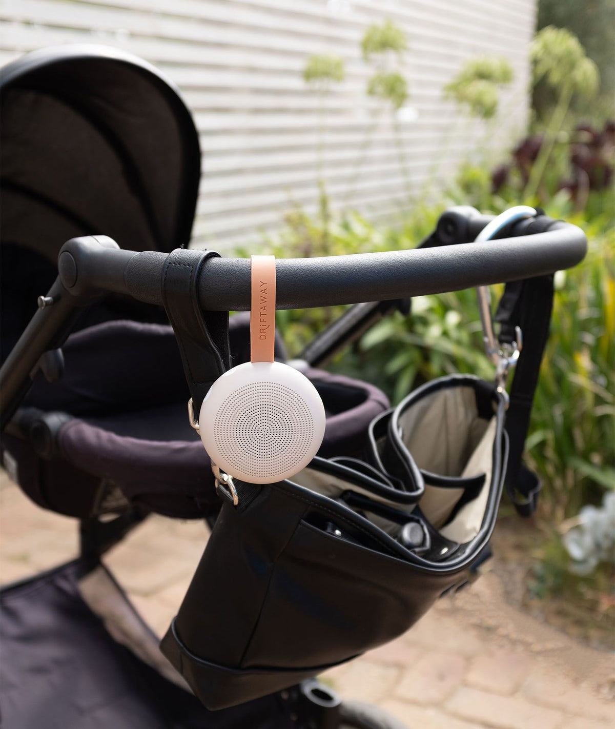 White round device attached to a stroller with a garden background