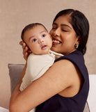 Woman holding a baby against a beige background