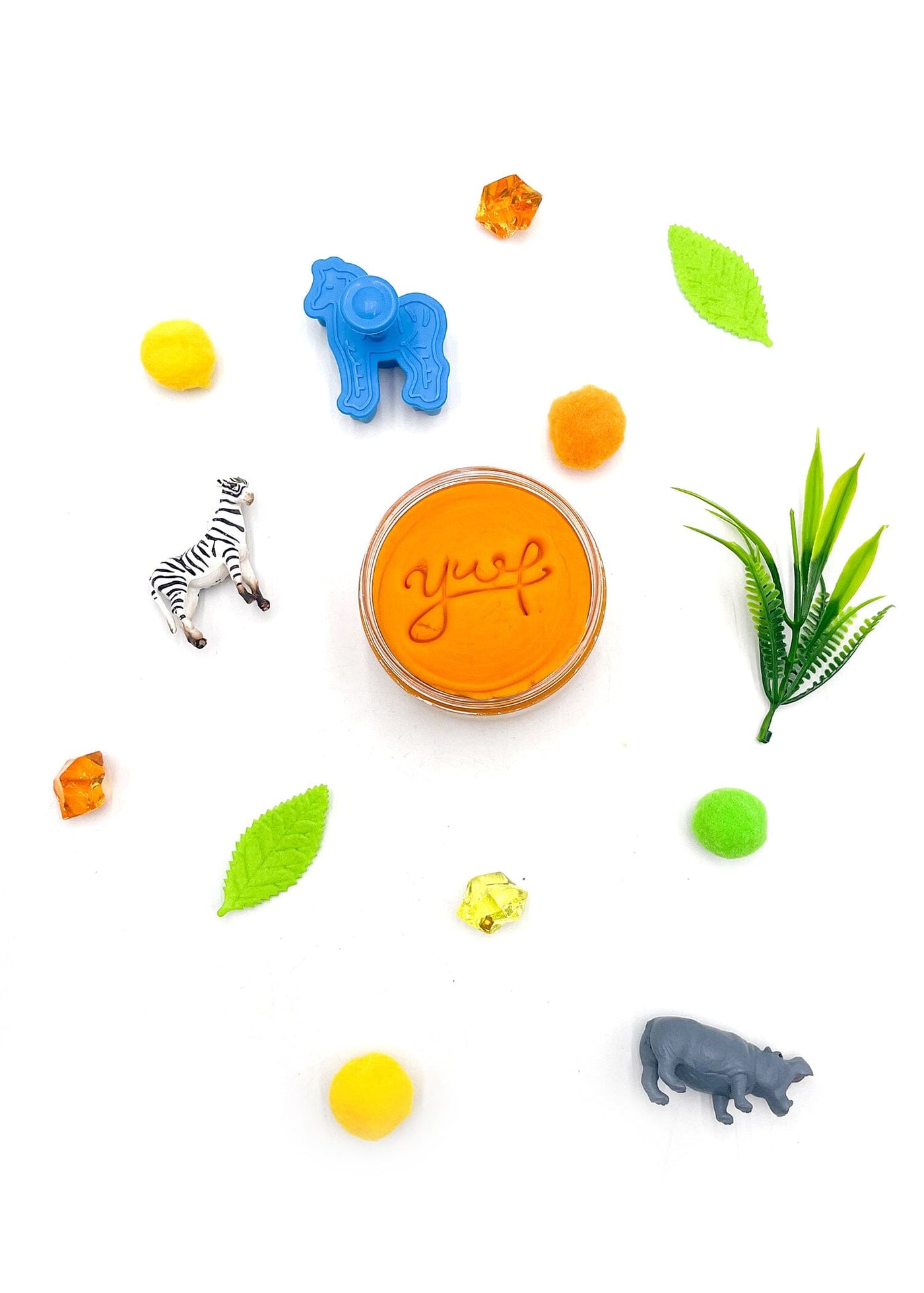 Small container of 'yup' jelly with animal figurines and leaves on a white background