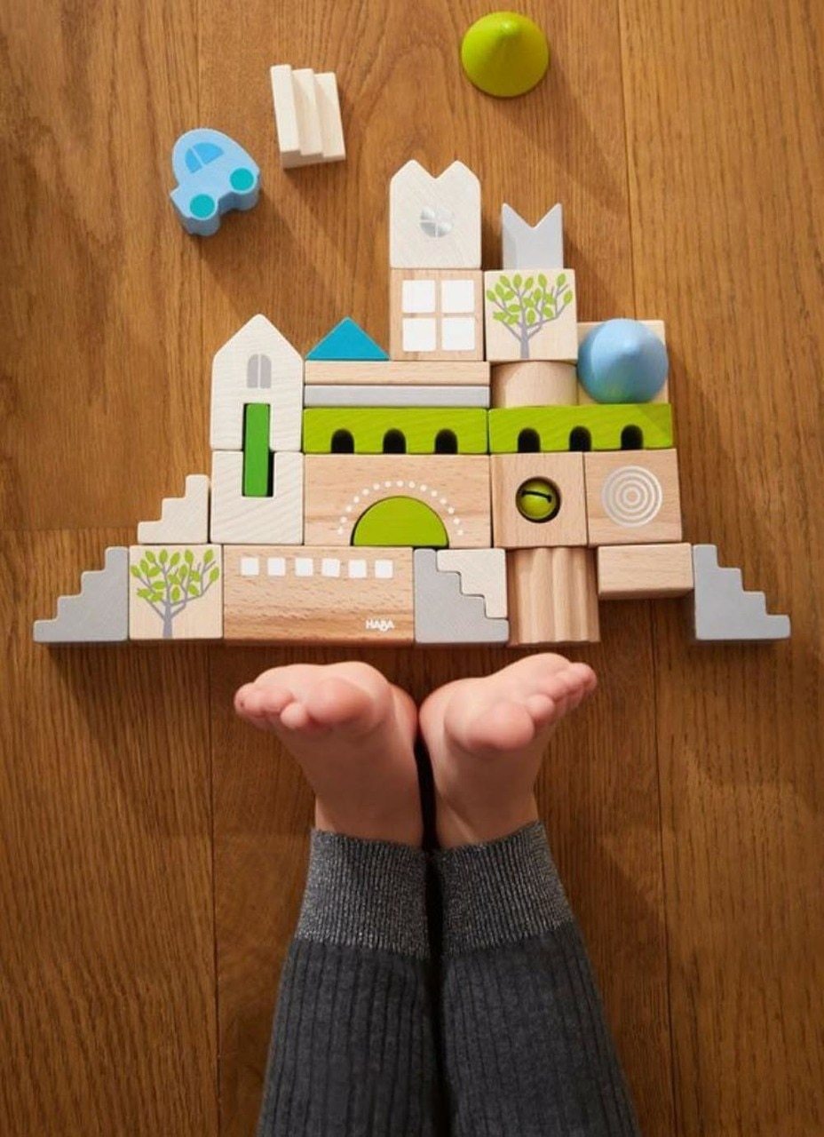 wooden building blocks on a wooden floor with a kids feet showing