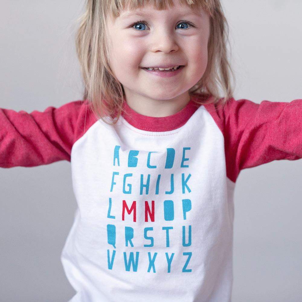 Up close image of blond girl wearing minnesota ABC shirt on a white background
