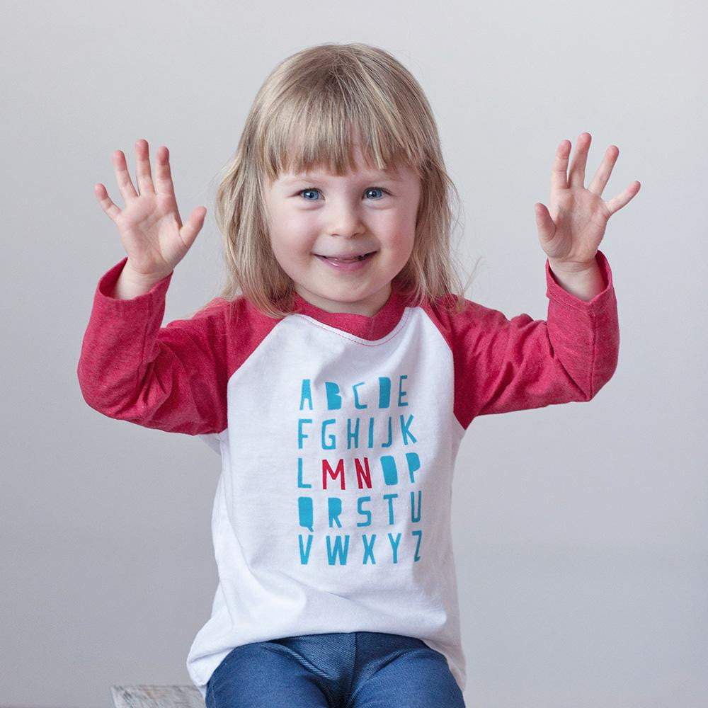Blond girl wearing minnesota ABC shirt with jeans on a white background